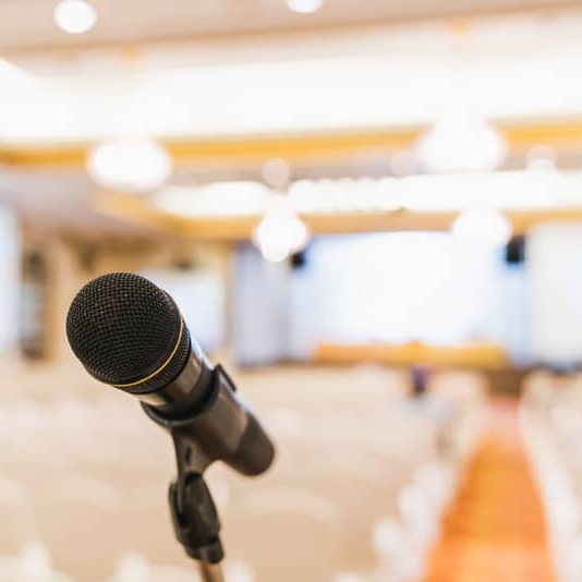 Microphone stand in conference hall blurred background with copy space. Public announcement event, Organization company meeting, live performance media, or graduation education award ceremony concept
